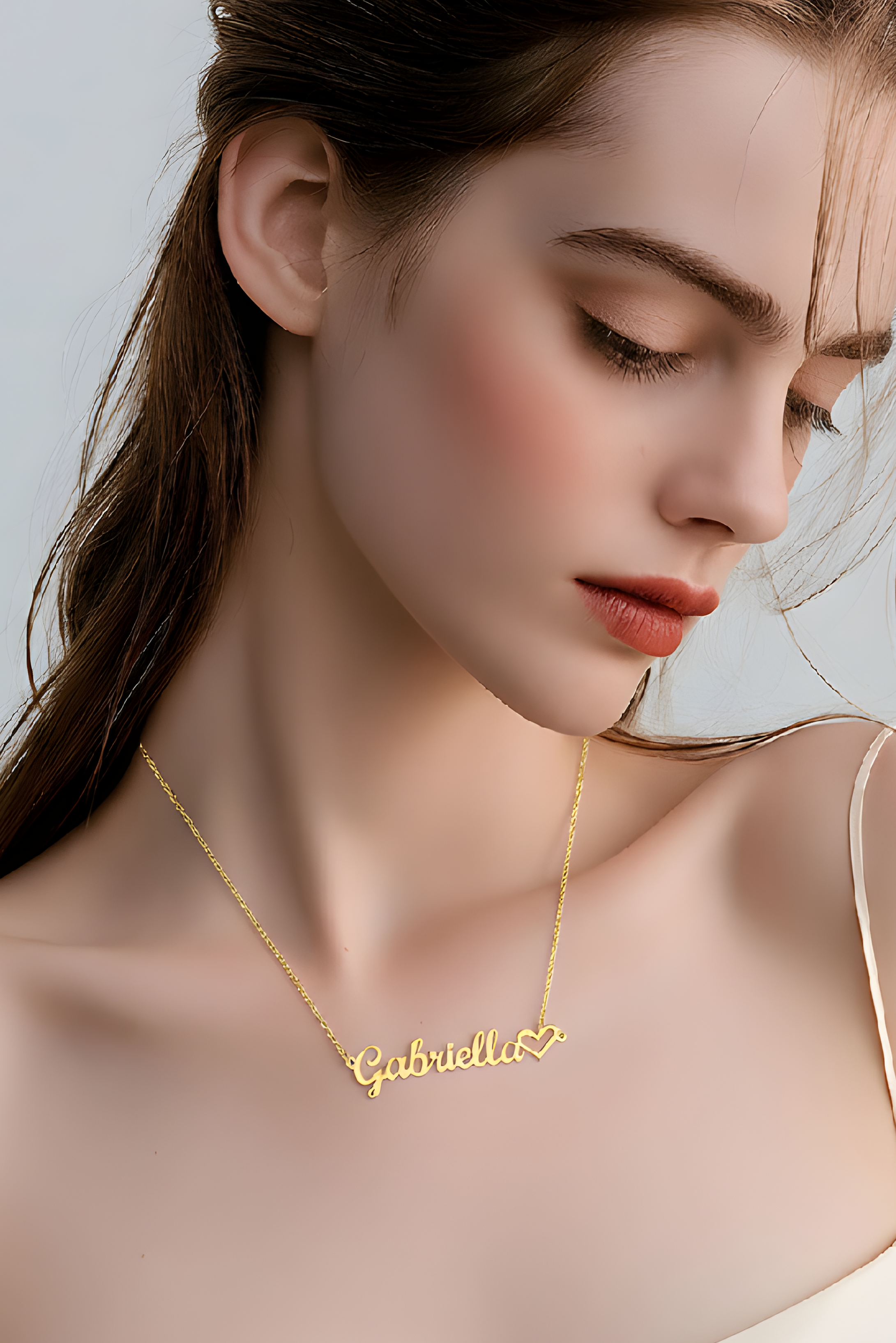 Woman wearing a gold necklace with 'Gabriella' on a plain background
